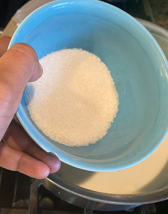 adding sugar to a pot