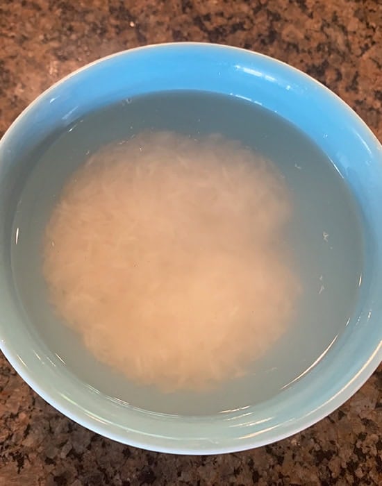 rice soaked in water in a blue bowl