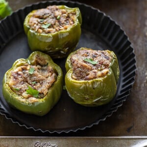 3 pieces of bharwa shimla mirch (stuffed bell peppers) arrange in a black round plate