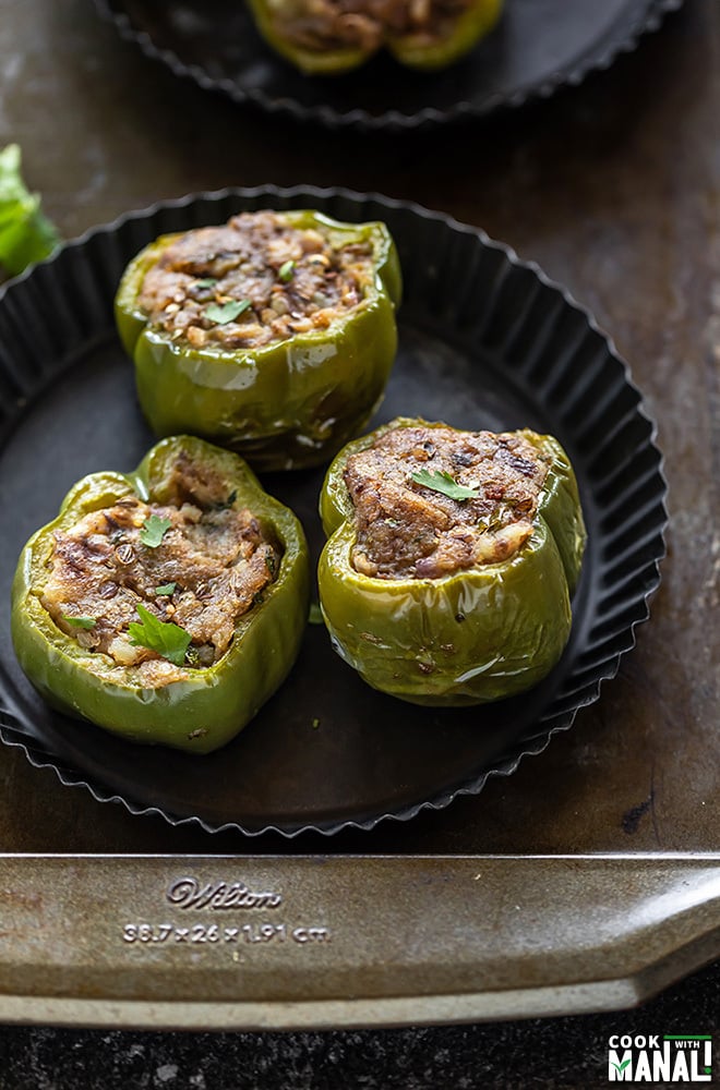 3 pieces of bharwa shimla mirch (stuffed bell peppers) arrange in a black round plate