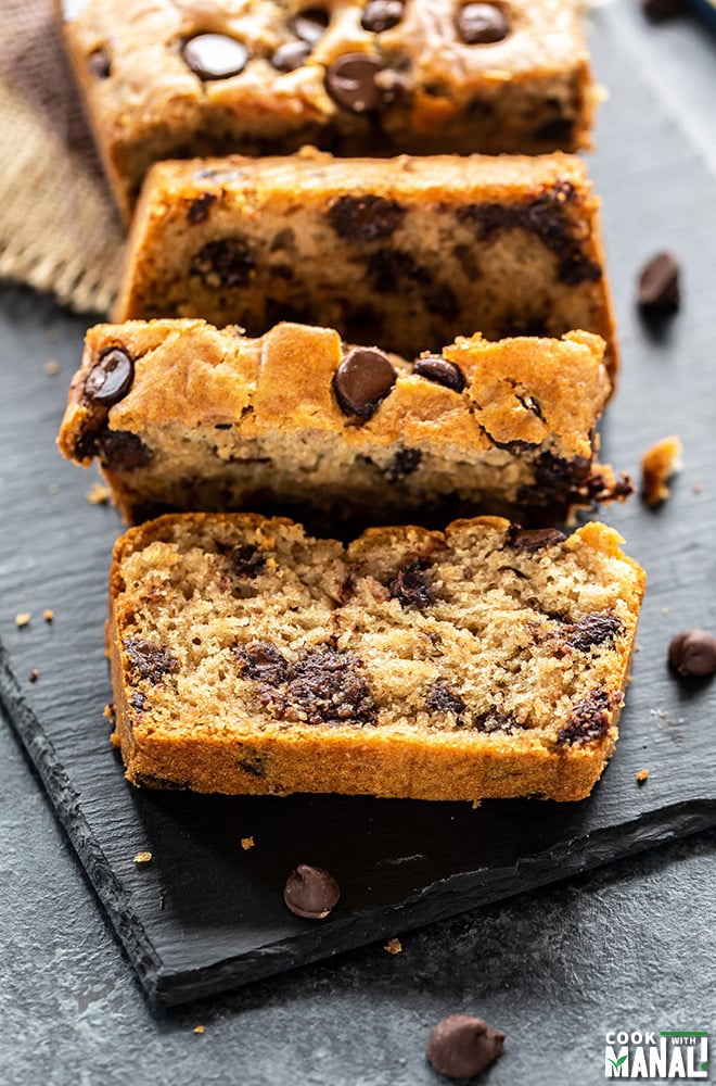 a slice of eggless chocolate chip cake being cut from the main loaf