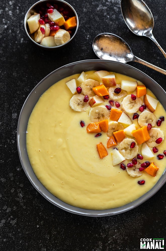 fruit custard served in a large grey bowl with spoons in the background