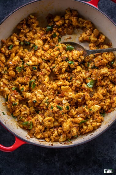 paneer bhurji served in a red pan and garnished with cilantro