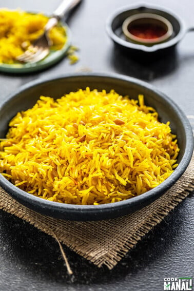 saffron rice in a black bowl with a small bowl of saffron strands in the background