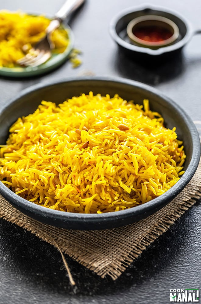 saffron rice in a black bowl with a small bowl of saffron strands in the background