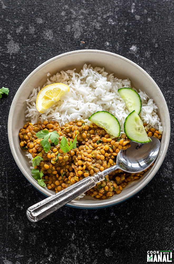 rice and whole masoor dal served in a bowl with sliced cucumbers