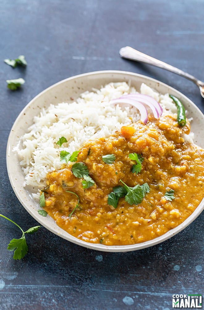 dal fry and rice served in a white plate garnished with cilantro