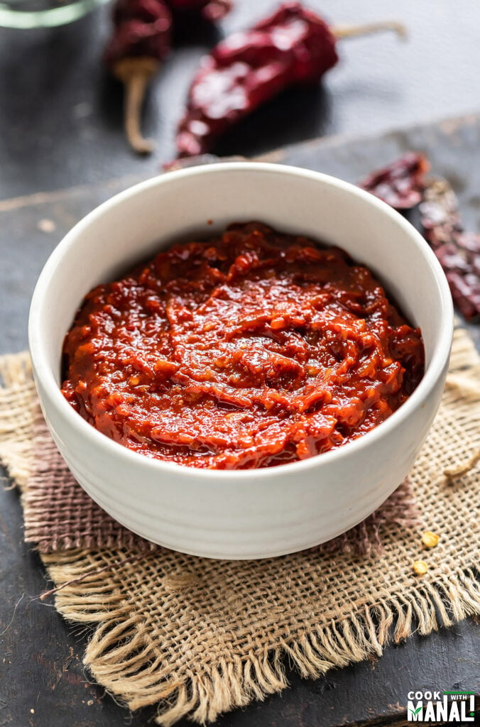 red color thick sauce in a white bowl with some red chilies place in the background