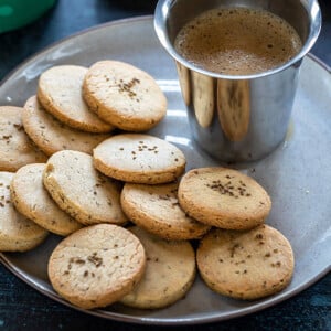 ajwain cookies in a plate with a glass of coffee