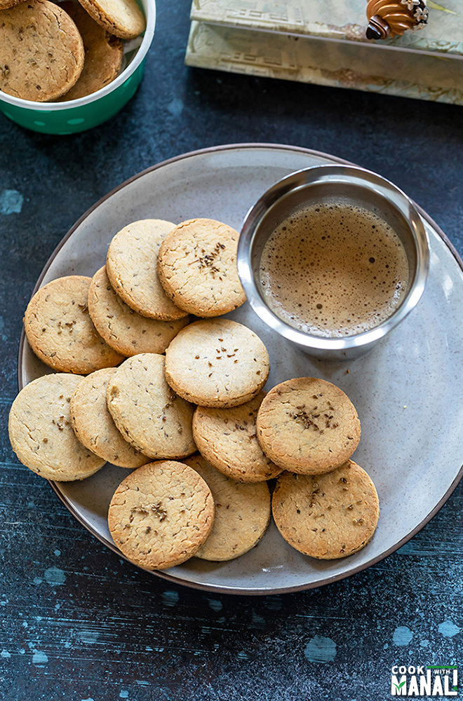 overhead shot of ajwain biscuits in a plate with a glass of coffee