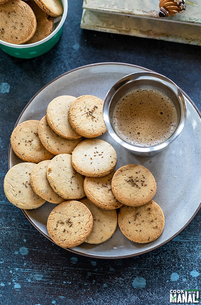 overhead shot of ajwain biscuits in a plate with a glass of coffee