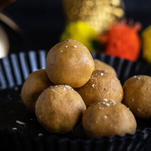 stack of besan ladoo in a plate with garlands placed in the background