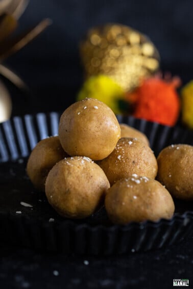 stack of besan ladoo in a plate with garlands placed in the background