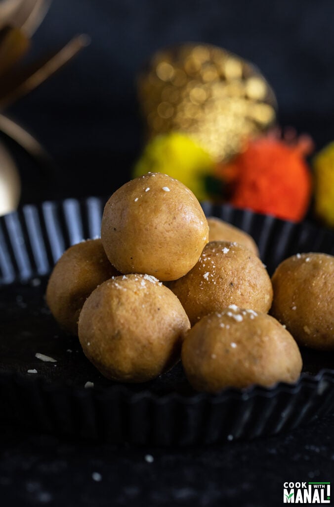 stack of besan ladoo in a plate with garlands placed in the background