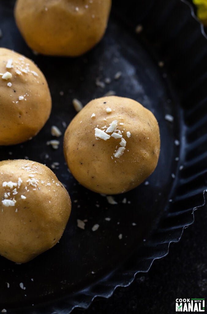 3 pieces of besan ladoo arranged in a plate and garnished with nuts