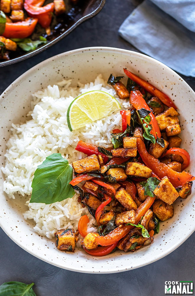 basil tofu stir fry served with jasmine rice in a white bowl garnished with lime wedge