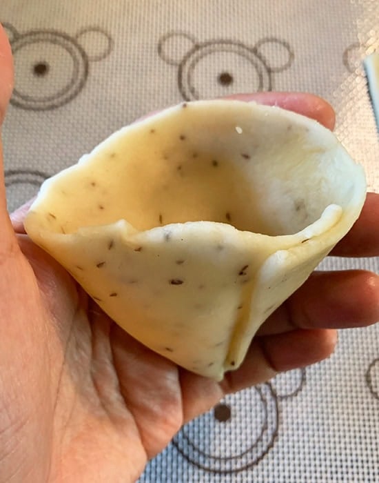 folding dough to give it a cone shape