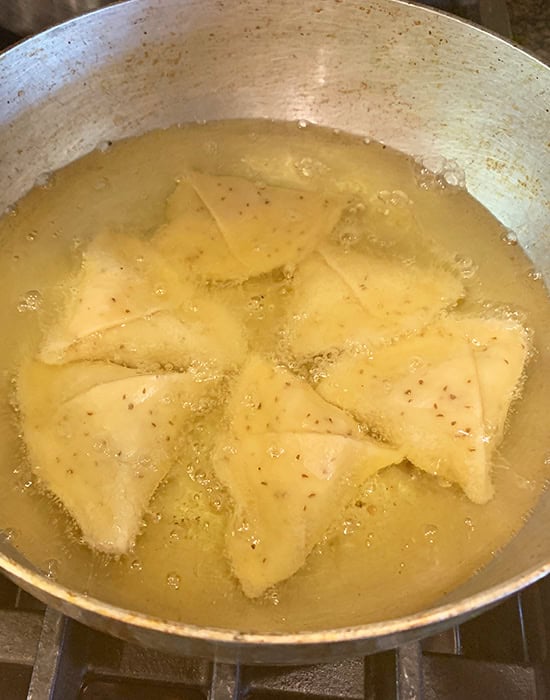 adding samosa to hot oil in a kadai