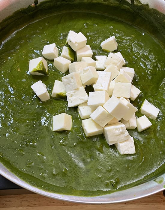 paneer cubes added to spinach puree in a pan