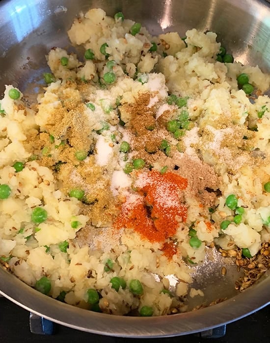 mashed potato and peas with spices in a pan