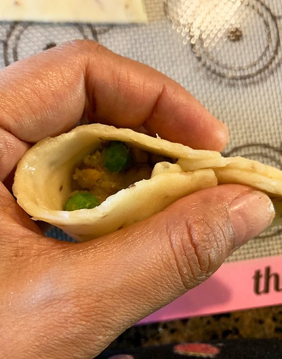 pinching the edges to seal the samosa