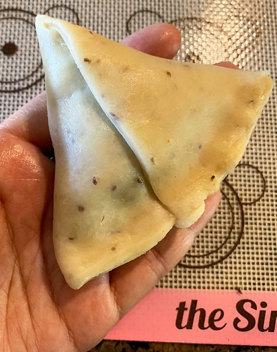 hand showing a sealed samosa