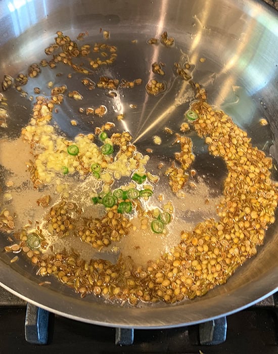 oil with spices, ginger and chilies in a steel pan
