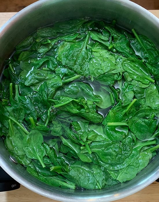 spinach leaves in boiling water in a pan