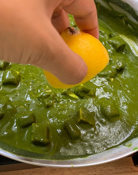 hand squeezing lemon juice into spinach puree