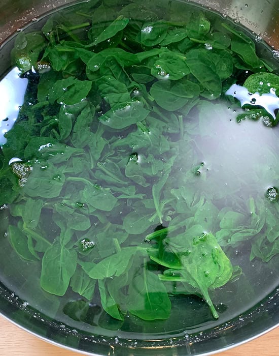 wilted spinach leaves in ice cold water