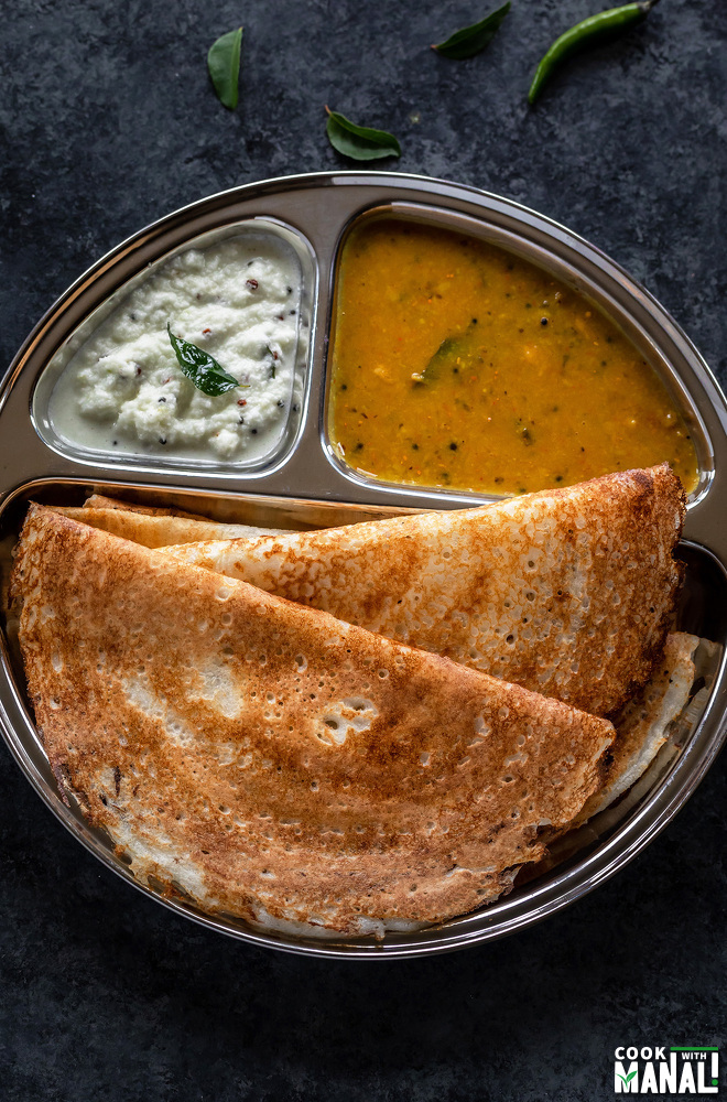 two crisp dosa served in a steel plate along with sambar and coconut chutney