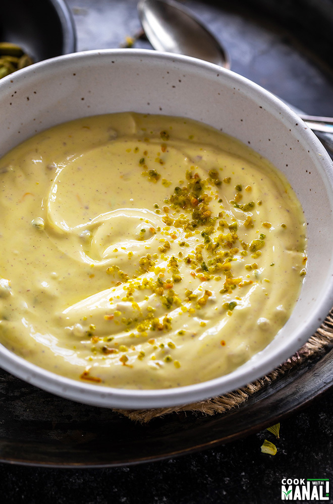 kesar pista shrikhand in a white bowl and garnished with pistachios