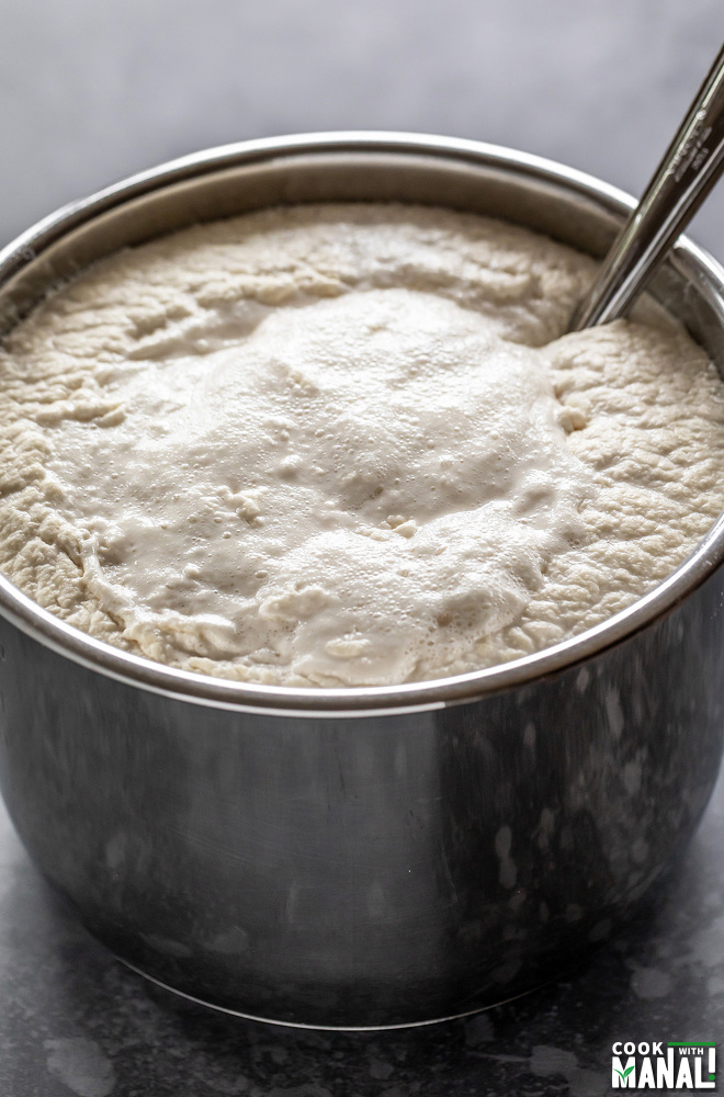 idli dosa batter in a steel pot with a ladle