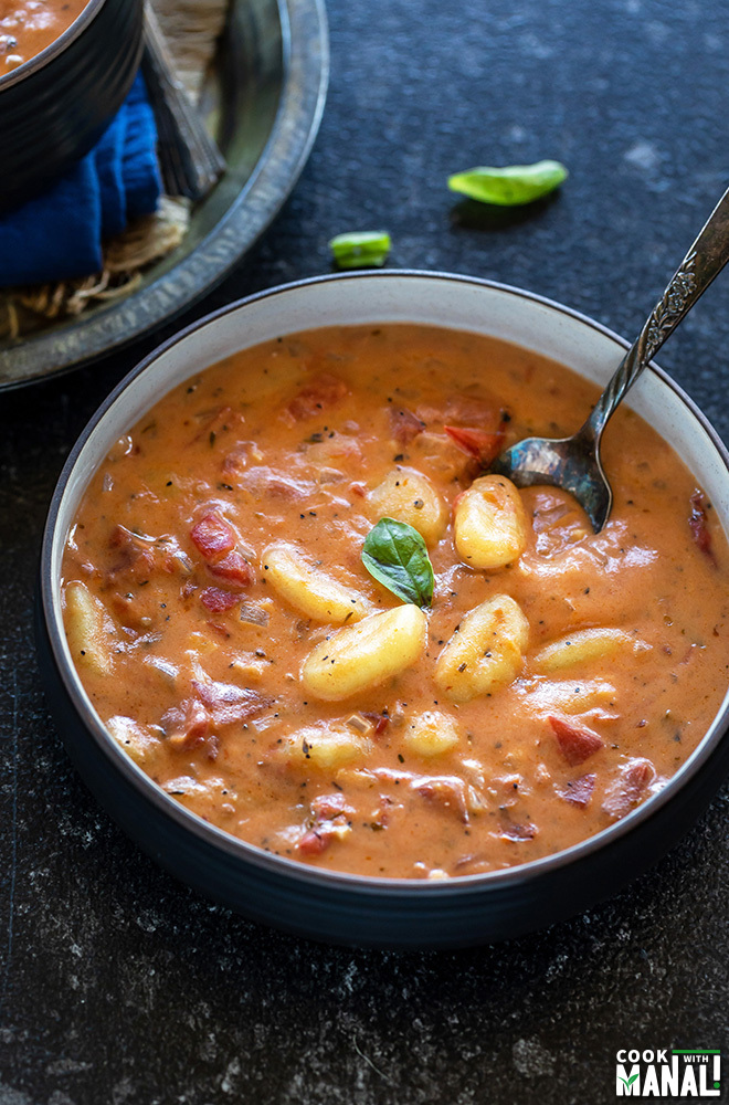 instant pot tomato gnocchi soup in a black bowl with a spoon