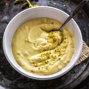 kesar pista shrikhand in a white bowl with a spoon