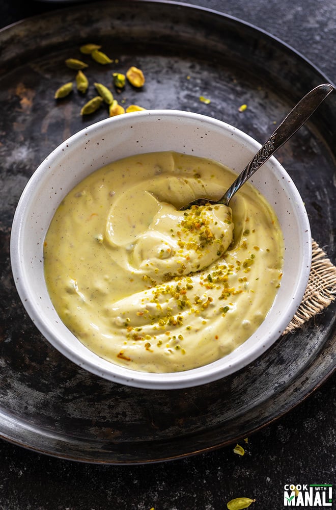 kesar pista shrikhand in a white bowl with a spoon