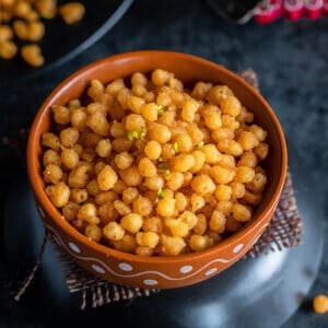 bowl of sweet boondi with a diya in the background