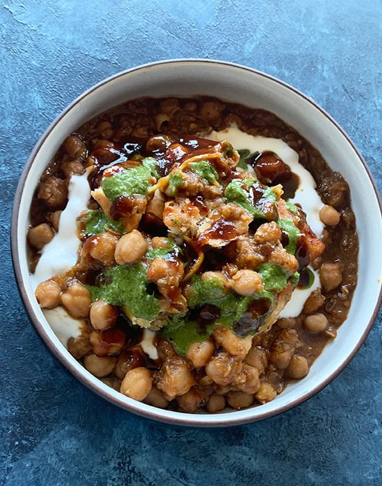 chole topped with samosa, yogurt and chutneys