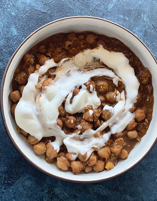 chole topped with yogurt in a round bowl