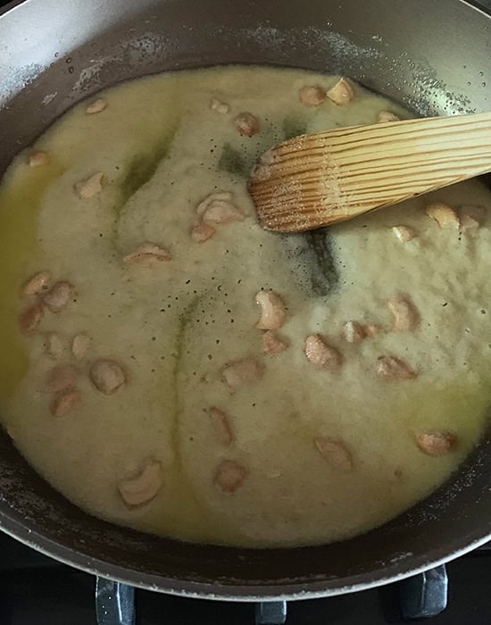 stirring sooji with ghee in a pan with a wooden spatula