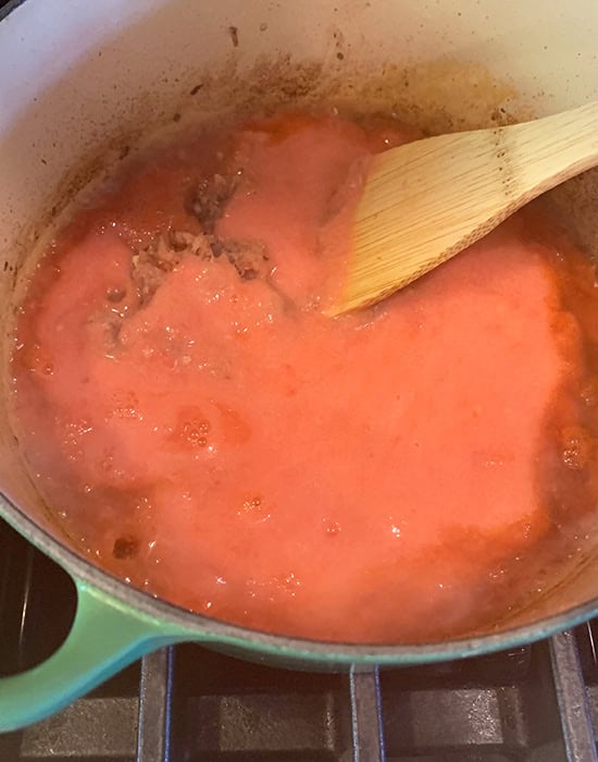 tomato puree in a pot with a wooden spatula