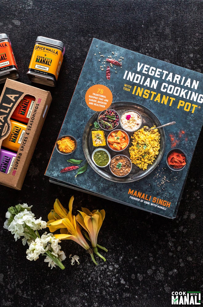 photo of vegetarian indian cooking with your instant pot cookbook along with a spice box and some flowers
