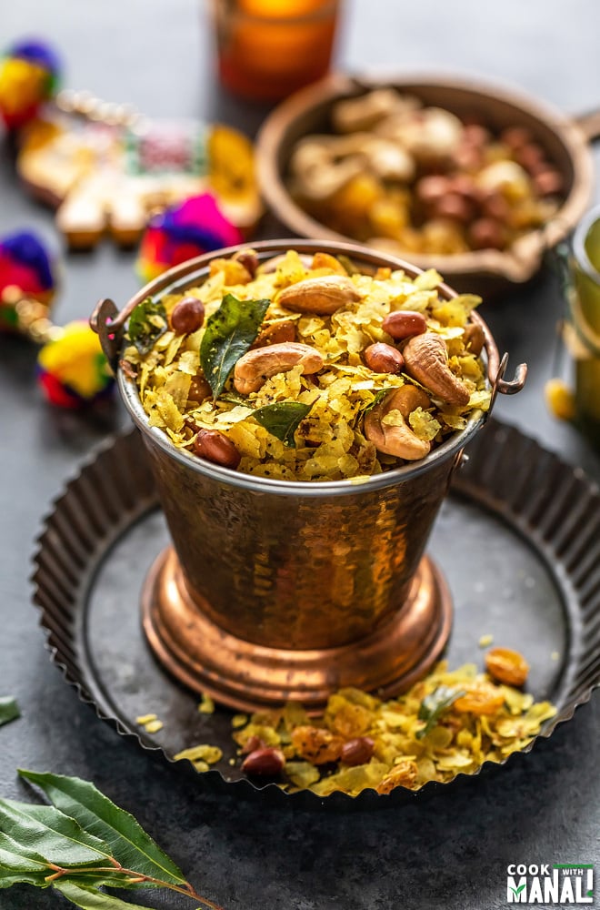 poha chivda served in a copper balti dish with decoration items and candles in the background