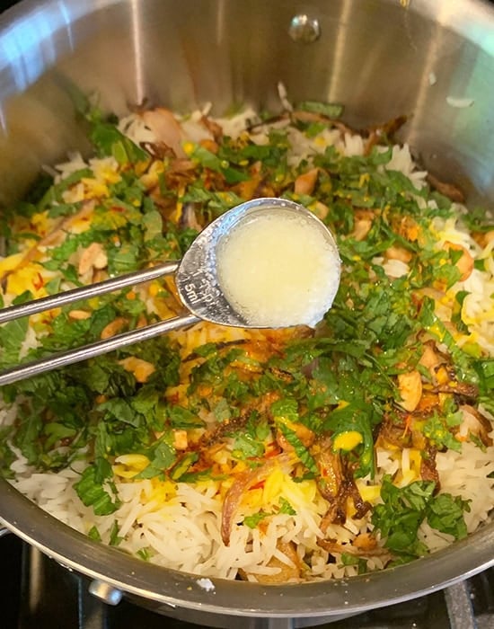 adding ghee on top of biryani