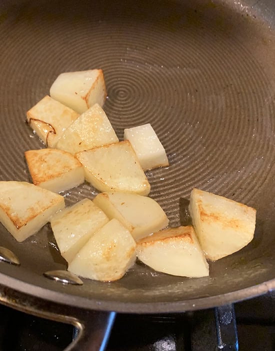 cubes of potato being fried in a pan