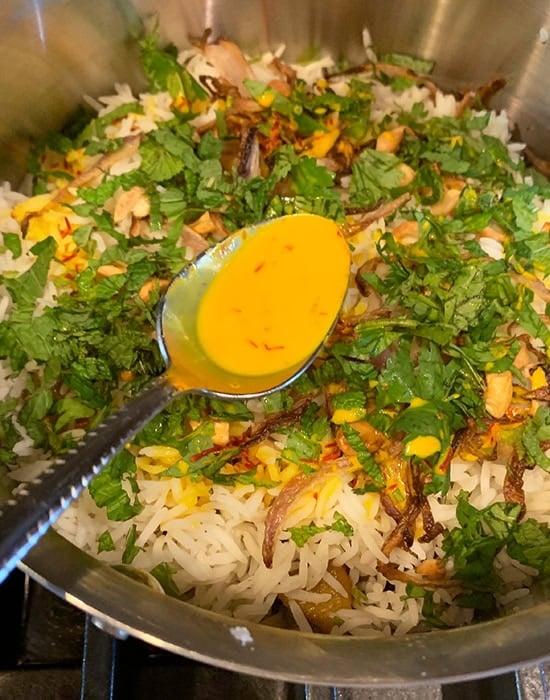 adding saffron milk on top of biryani