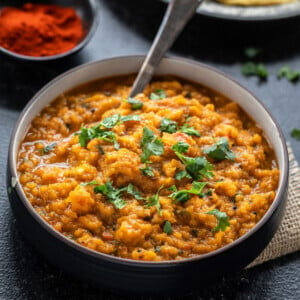 mashed butternut squash in a bowl with some flatbreads placed in the background