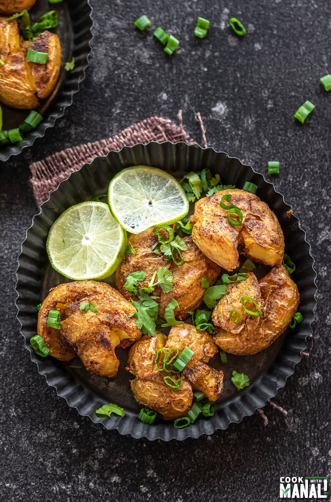 smashed potatoes served in a rimmed rustic plate with lime slices