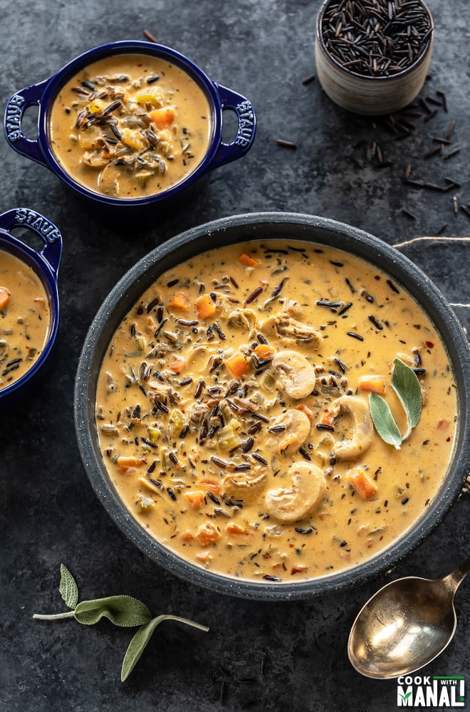 bowl of mushroom wild rice soup with two smaller soup bowl on the side