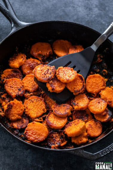 cast iron skillet with maple chili glazed sweet potatoes arranged in it